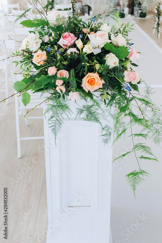 Indoor wedding ceremony with white wedding arch decorated with flowers and big white candles © Alexandr
