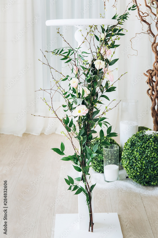 Indoor wedding ceremony with white wedding arch decorated with flowers and big white candles Indoor wedding ceremony with white wedding arch decorated with flowers and big white candles