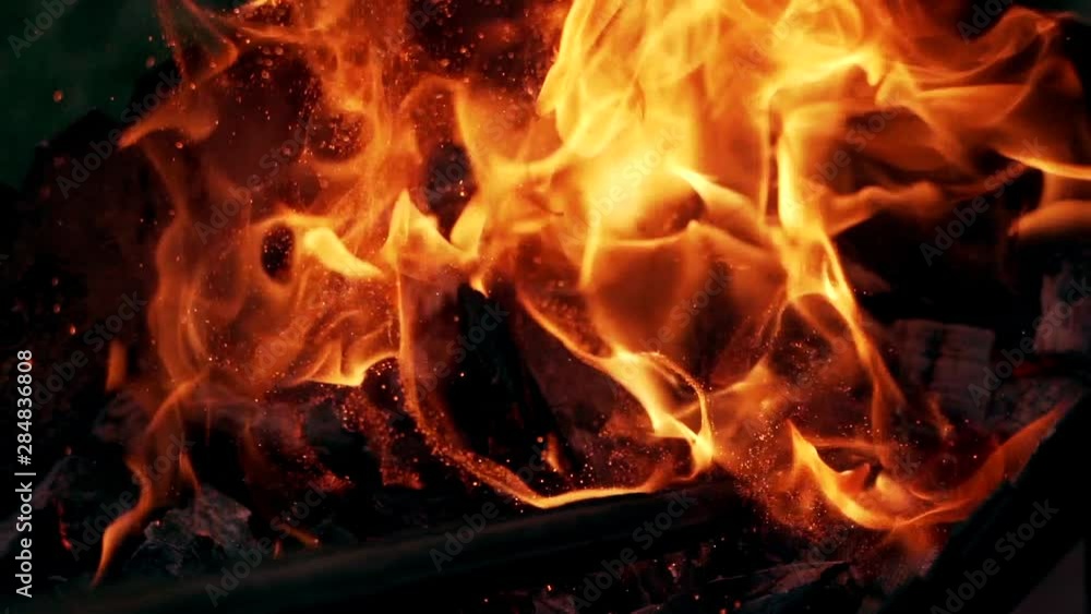 Bright sparkles flying from the fire at night. Wooden stick break smoldered logs in fire and flame becomes brightly outdoors. Slow motion. Bright sparkles flying from the fire at night. Wooden stick break smoldered logs in fire and flame becomes brightly outdoors. Slow motion.