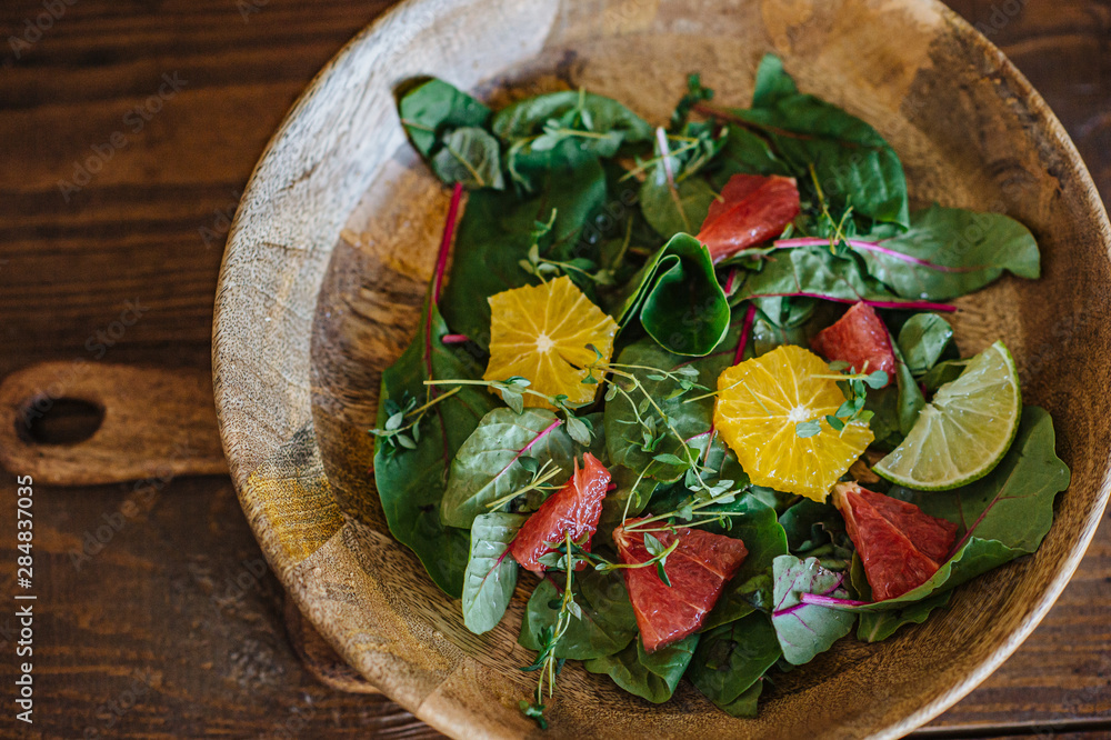 Crop hand passing green salad in white bowl while friends eating together Crop hand passing green salad in white bowl while friends eating together