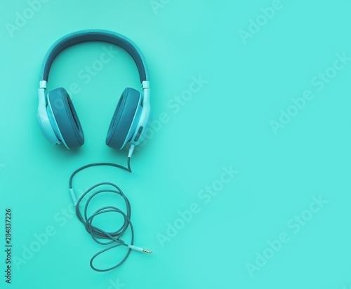 Turquoise headphones on a colored background. Music concept with copyspace. Colored headphones isolated