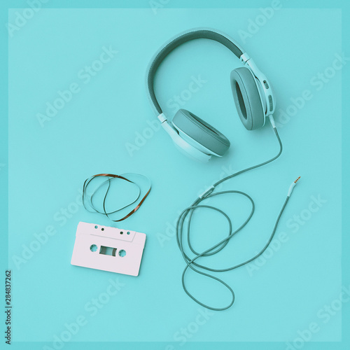 Turquoise headphones with audio cassette on a colored background. Music concept with copyspace. Colored headphones isolated