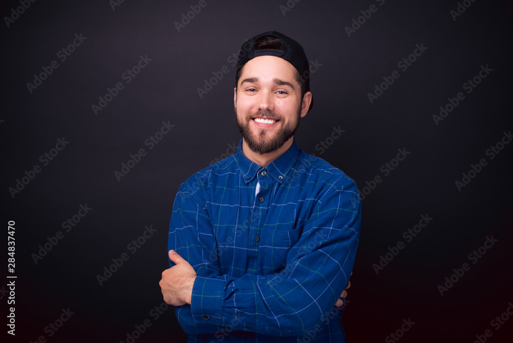 Photo of charming young smiling bearded man in blue shirt looking at the camera Photo of charming young smiling bearded man in blue shirt looking at the camera