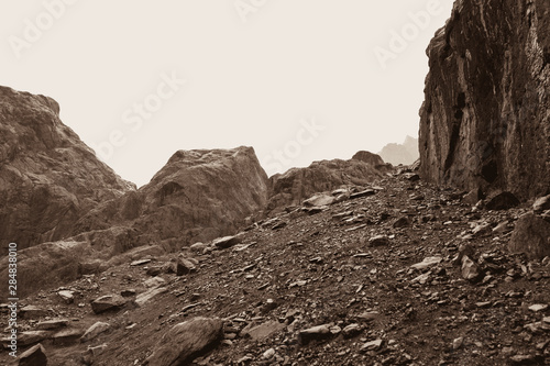 A sloping slope covered with loose stones. Difficult climb to Aktru. Beautiful views of the mountains on a tour of the nature of Altai land. Hiking and mountain climbing in the mountains. Toned sepia.