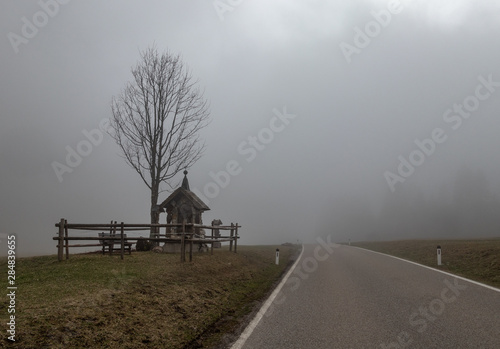 Billede på lærred The old chapel in a fog  Alps, Austria
