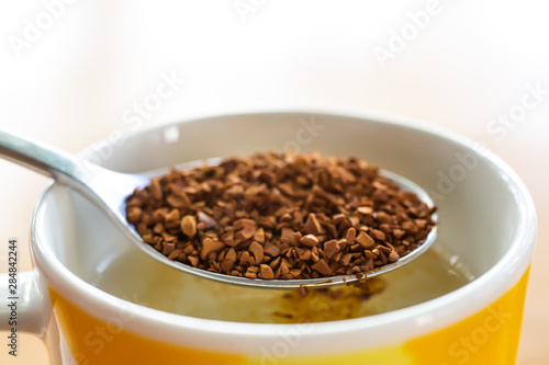 Spoon of Instant coffee granules pour in cup of coffee, White background, Close up & Macro shot, Selective focus, Relax time, Drink concept