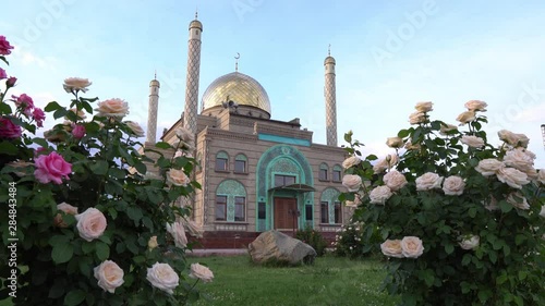  Zharkent Golden Cupola Mosque Breathtaking Picturesque Frontal View with White Colored Roses in Front on a Sunny Blue Sky Day photo