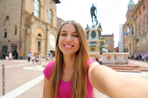 Beautiful Italy. Attractive smiling young woman take self portrait in Piazza del Nettuno square Bologna city, Italy. © zigres