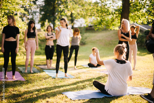 Obraz na plátně Yoga woman coach welcomes his students and gives instructions in park at dawn