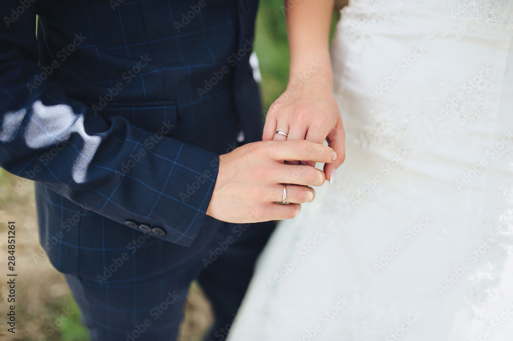 Newlyweds show hands with wedding rings. The bride and groom hold hands. Wedding day and ceremony. Portrait and photograph of lovers.