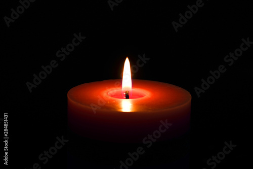 Single candle red flame isolated on black with selective focus