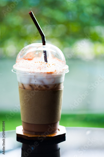 Glass of iced coffee mocha with chocolate powder and milk foam