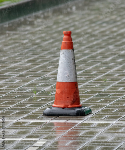 white-orange road cone on a rainy day