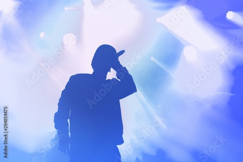 Silhouette of rap singer performing on concert. Rapper singing on stage in night club. Hip hop images for poster design photo
