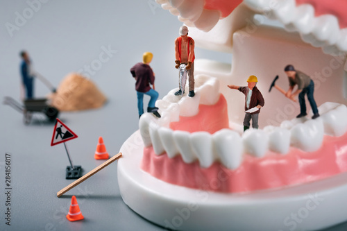 Fotografie dental treatment concept - construction workers figurines on tooth model