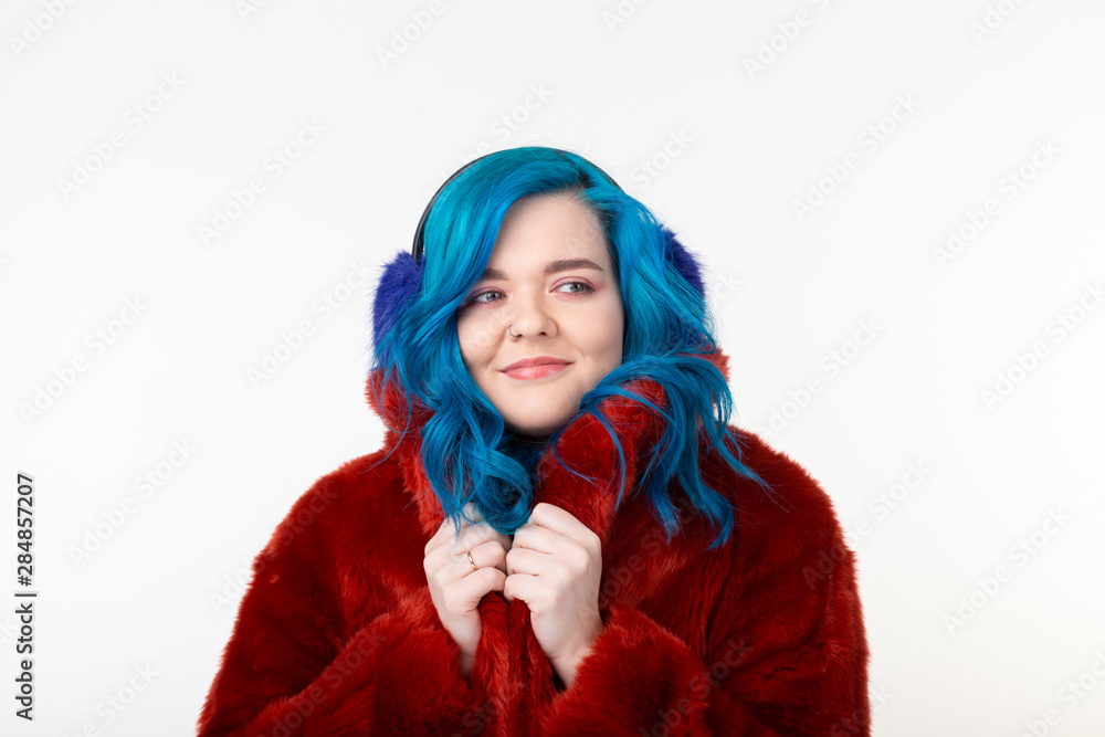 People, protection animals and fashion concept - Beautiful girl with blue hair dressed in red warm jacket in artificial fur and earmuffs People, protection animals and fashion concept - Beautiful girl with blue hair dressed in red warm jacket in artificial fur and earmuffs