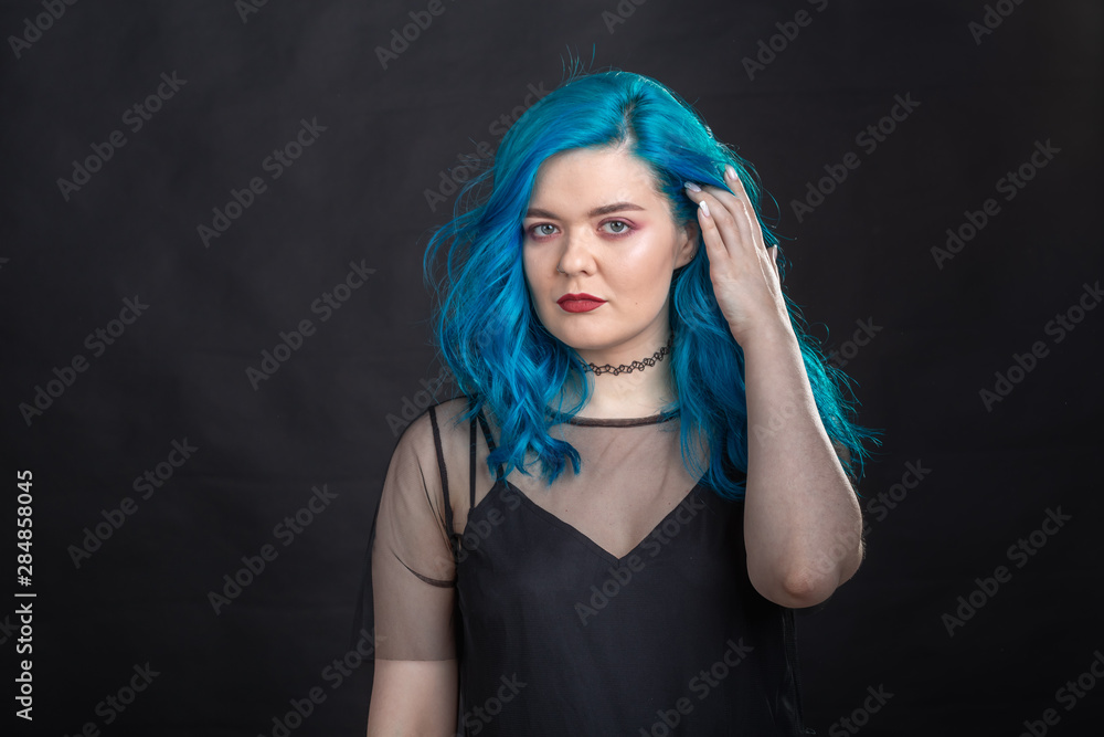 Obraz premium People and fashion concept - Young and attractive woman with black lipstick and blue hair posing over black background