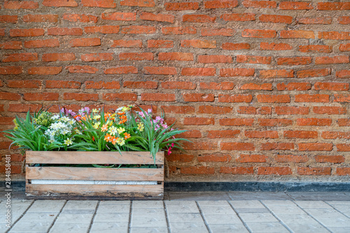 a basket of flowers was decorated in front of vintage red brick wall background