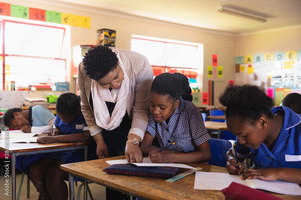Teacher helping schoolchildren in a lesson at a township school Teacher helping schoolchildren in a lesson at a township school