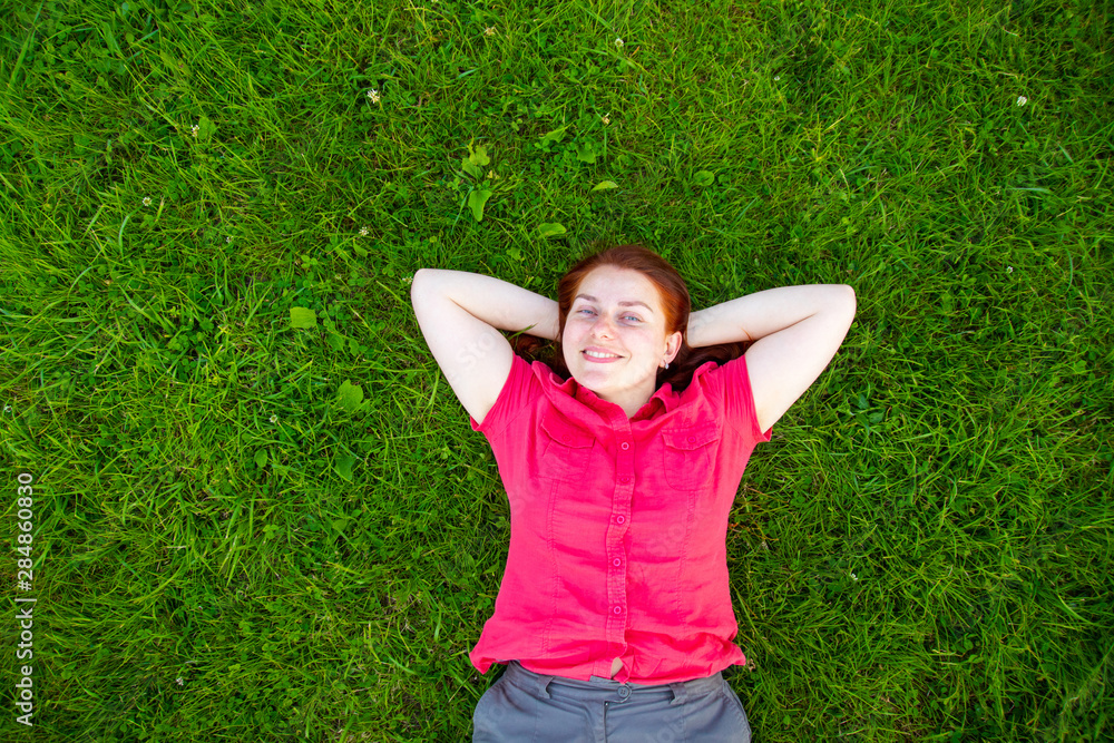 Portrait of a smiling red-haired young girl on green grass Portrait of a smiling red-haired young girl on green grass