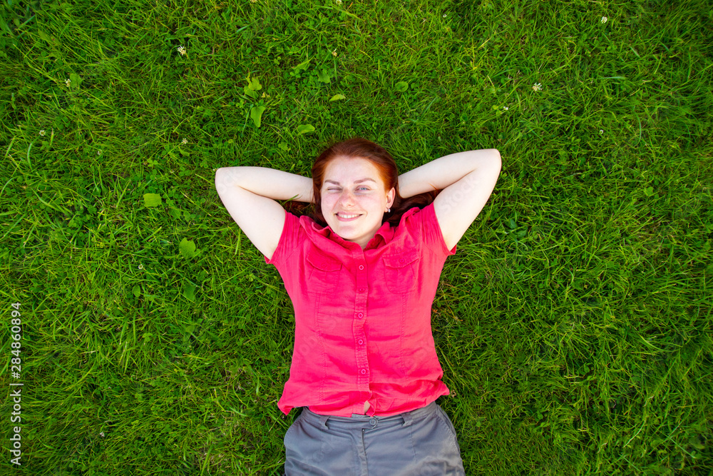 Portrait of a smiling red-haired young girl on green grass Portrait of a smiling red-haired young girl on green grass