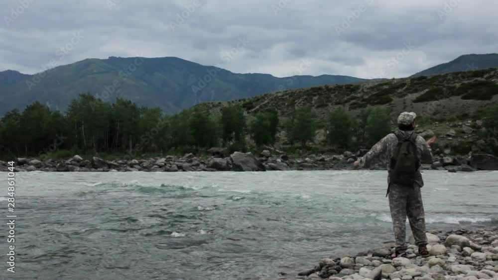 single fisherman on a stormy river is fishing on a sunny summer day