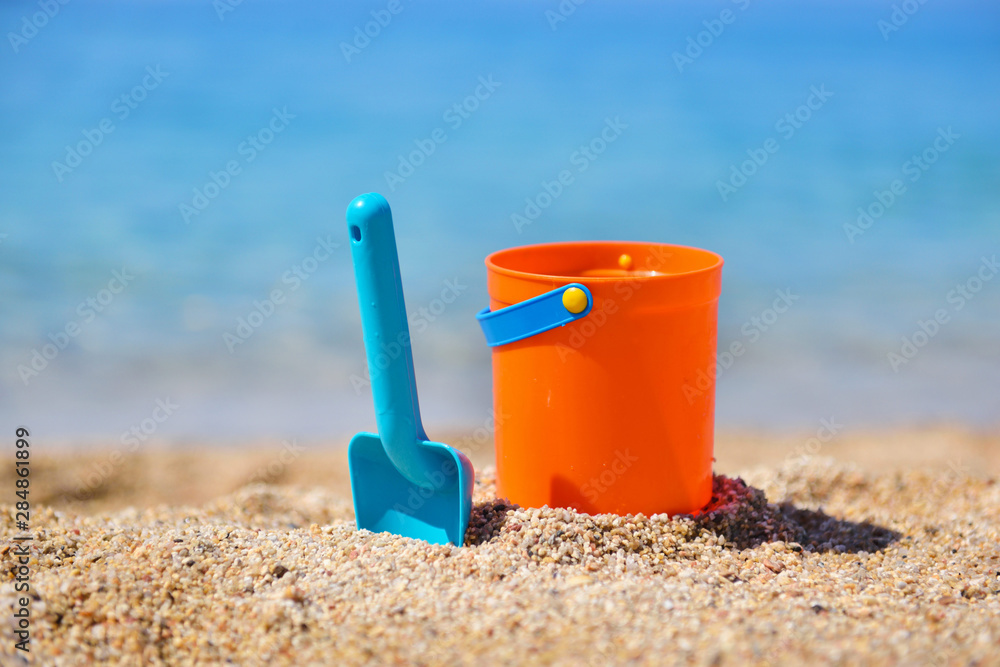 Bright plastic сhildren's beach toys on sand near sea. Summer vacation concept Bright plastic сhildren's beach toys on sand near sea. Summer vacation concept