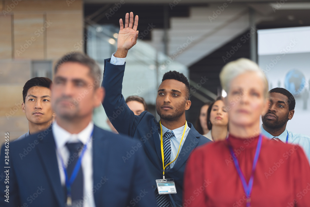 Young businessman raising hand in a business seminar Young businessman raising hand in a business seminar