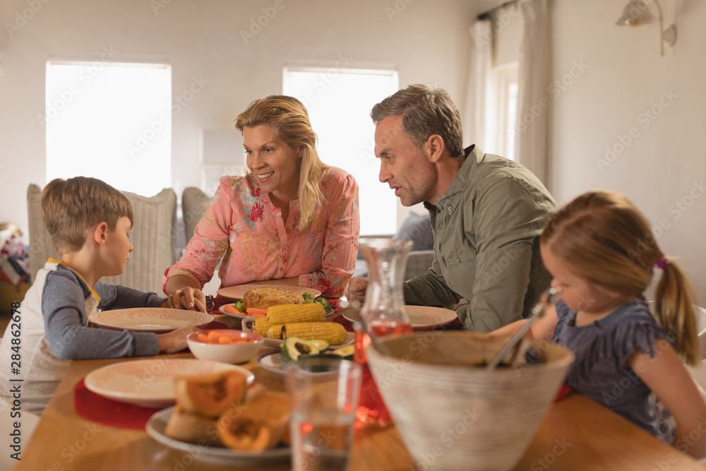Family interacting with each other while having food on dining table Family interacting with each other while having food on dining table