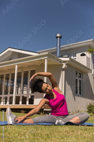 Woman performing stretching exercise in the backyard of home