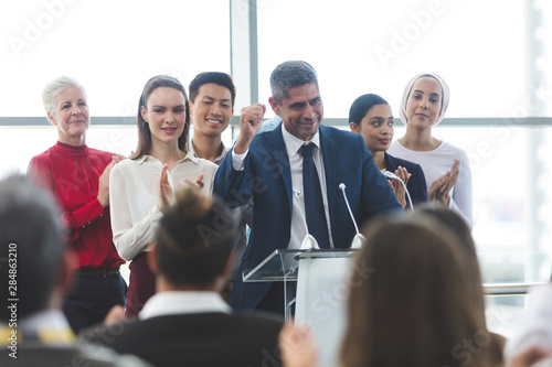 Businessman standing at podium with colleagues and speaks in a business seminar