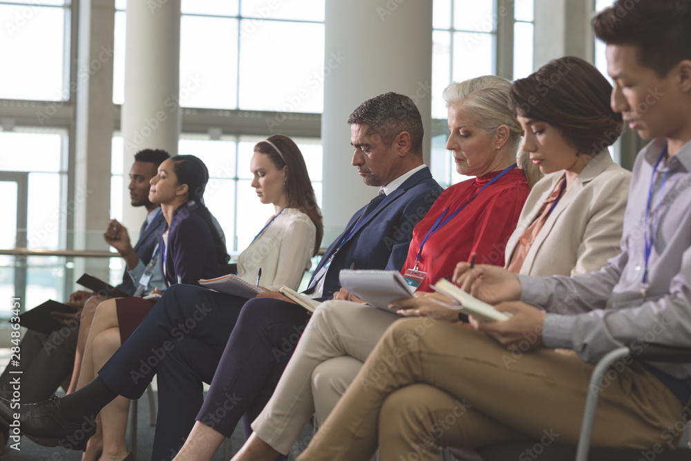 Business people writing on notepad in a business seminar