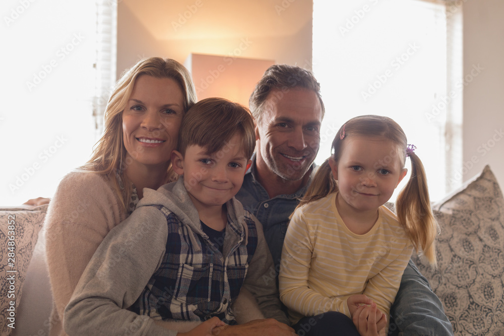 Obraz premium Happy family sitting together on sofa in living room at home