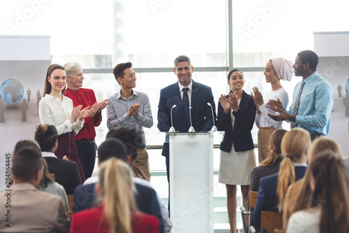 Businessman standing at podium with colleagues and speaks in a business seminar