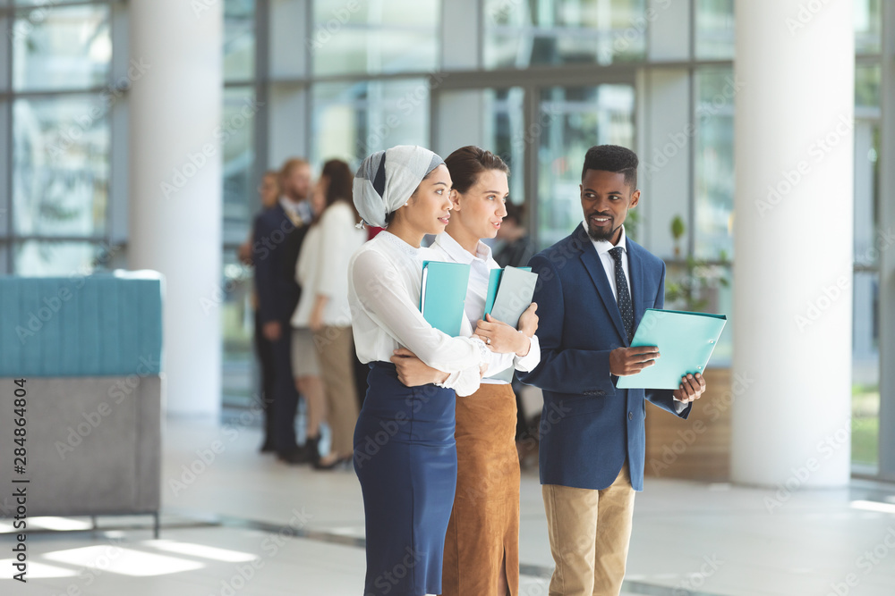 Business executives standing with files in lobby office Business executives standing with files in lobby office