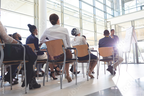 Group of young business people listening to businessman in conference room