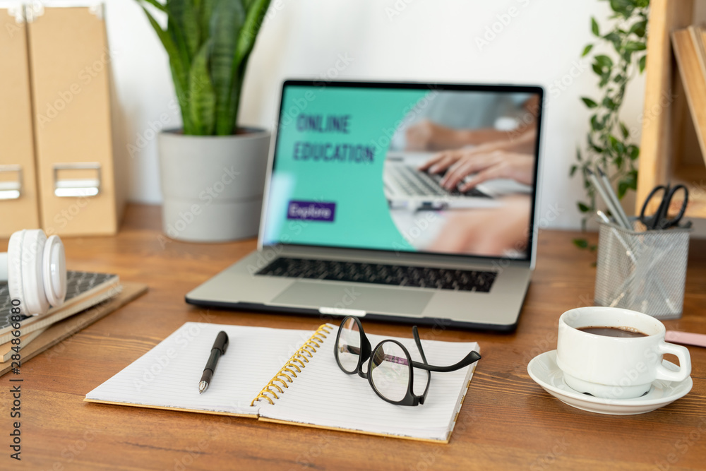 Open notebook with pen and eyeglasses on blank pages and cup of coffee on desk Open notebook with pen and eyeglasses on blank pages and cup of coffee on desk