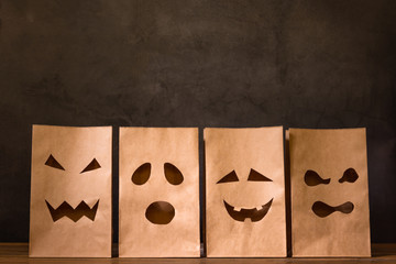 paper bags with scary face on wooden table, halloween concept