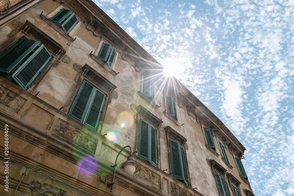 Obraz premium Italian renaissance windows with shutters. Sun flair and blue sky. Ferrara, Italy.