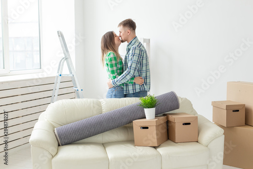 Young couple in denim pants embracing rejoicing in their new apartment during the move. The concept of housewarming and credit for new housing.