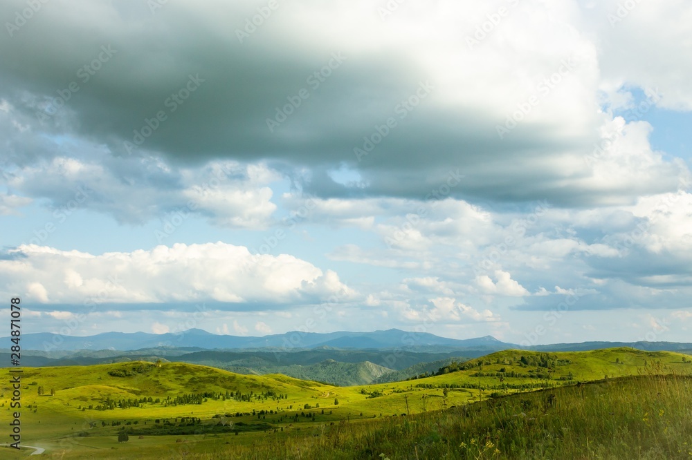 Hills with green grass and blue sky with white puffy clouds