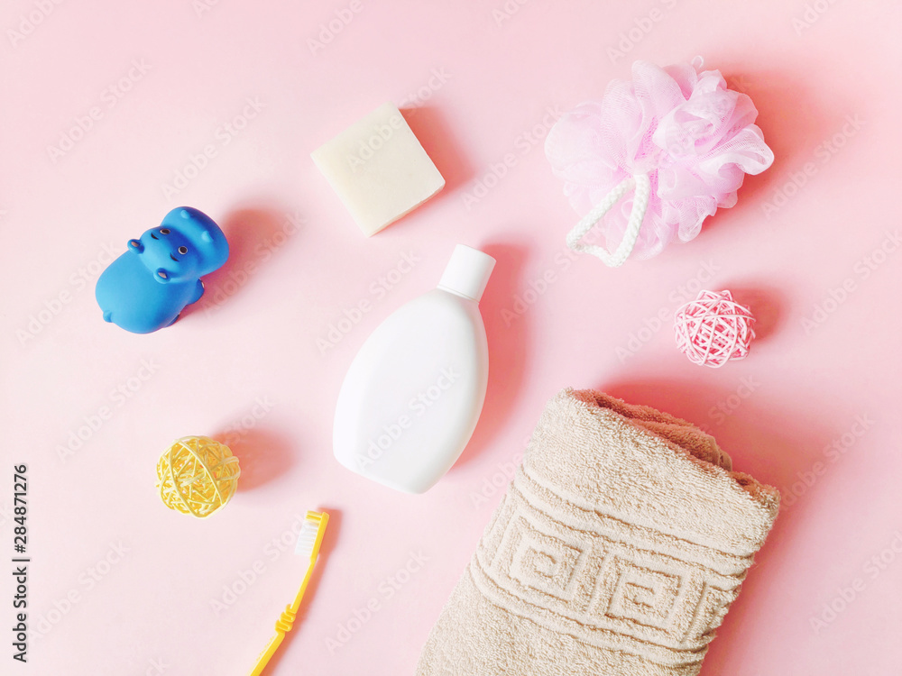 Flat lay photo baby care products on a pink background. Shampoo, soap, toothbrush, beige towel and rubber toy hippo Flat lay photo baby care products on a pink background. Shampoo, soap, toothbrush, beige towel and rubber toy hippo