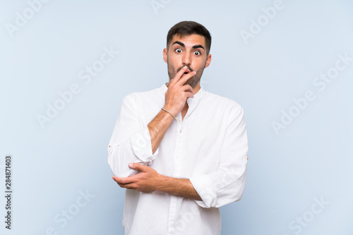 Handsome man with beard over isolated blue background surprised and shocked while looking right © luismolinero