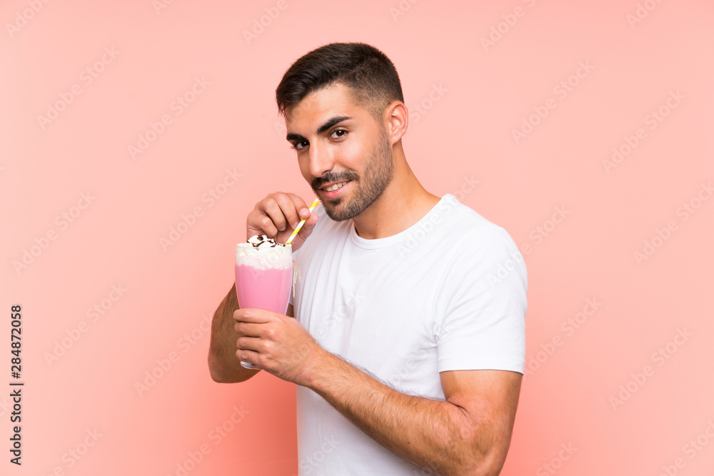Young man with strawberry milkshake over isolated pink background Young man with strawberry milkshake over isolated pink background
