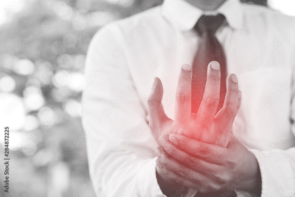 businessman having Injury wrist pain in hands while work outdoor symptomatic office syndrome. health care concept. black and white. Focus red body on to show pain. 