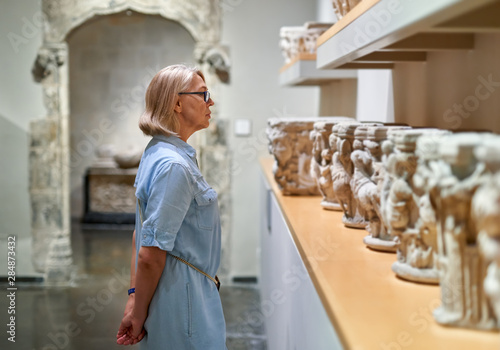Tableau sur toile Woman visitor in historical museum looking at art object.