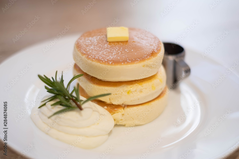 Honey pancakes and butter on the white dish.