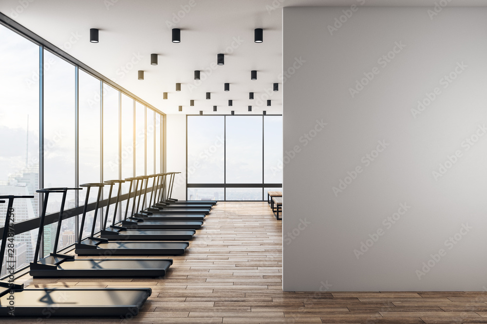 Fototapeta premium Biała pusta ściana w nowoczesnej siłowni z drewnianą podłogą