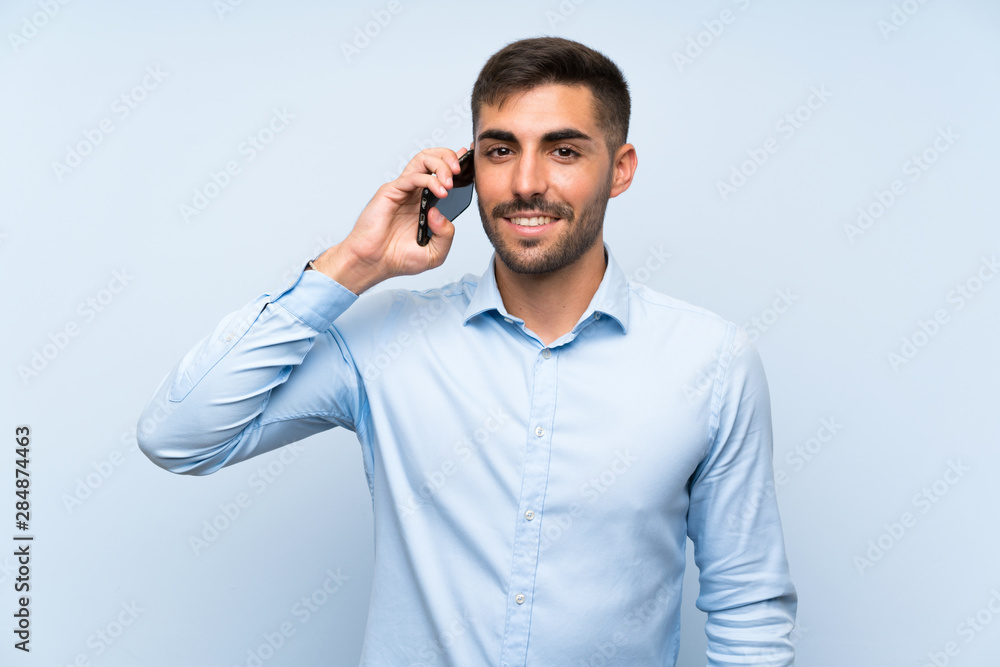 Young handsome man with his mobile over isolated blue wall Young handsome man with his mobile over isolated blue wall