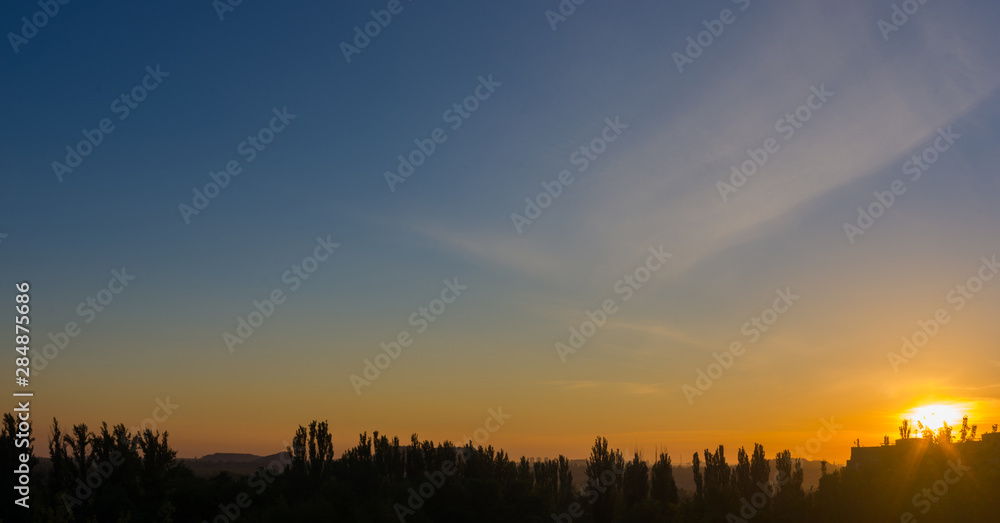 Landscape with dramatic light - beautiful golden sunset with saturated sky and clouds.